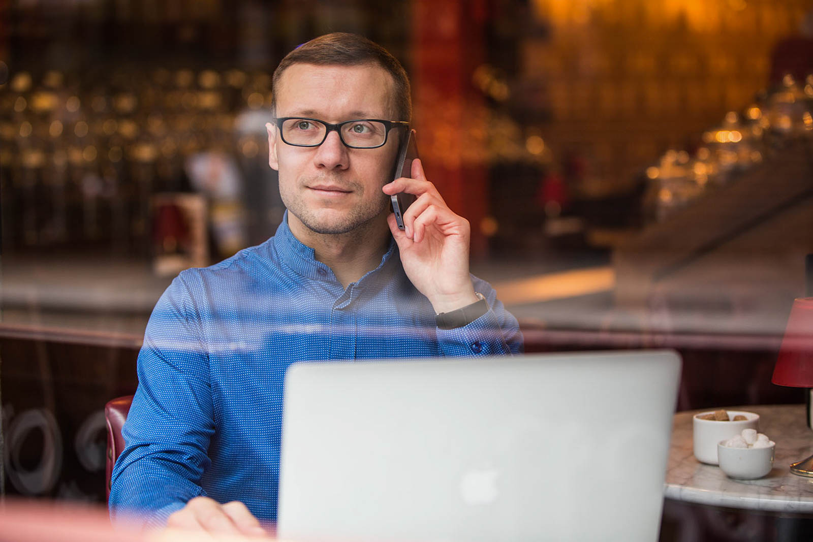 Dublin headshot of man sitting in coffee shop while on phone with laptop