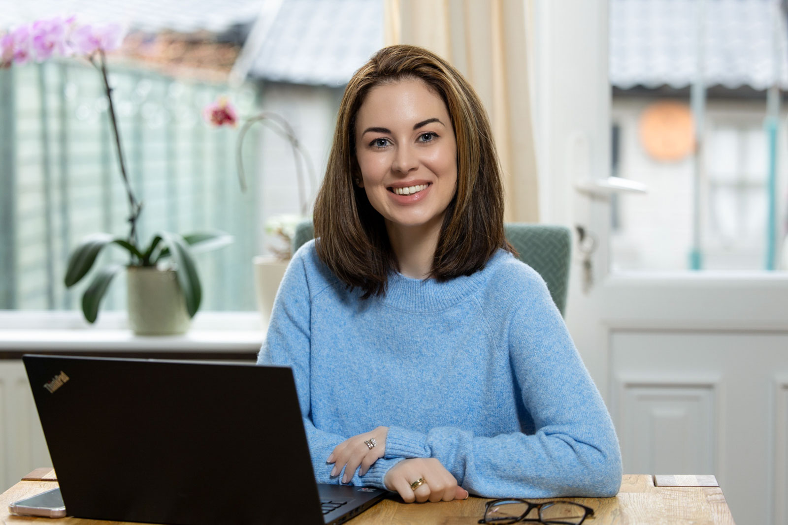 Relaxed Dublin headshot of woman at kitchen table with laptop smiling